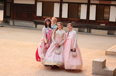 A group of women in dresses posing for a photo

Description automatically generated